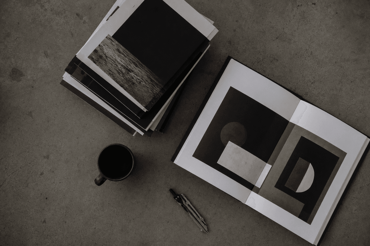Editorial overhead flat-lay of a curated work archive on cool grey concrete