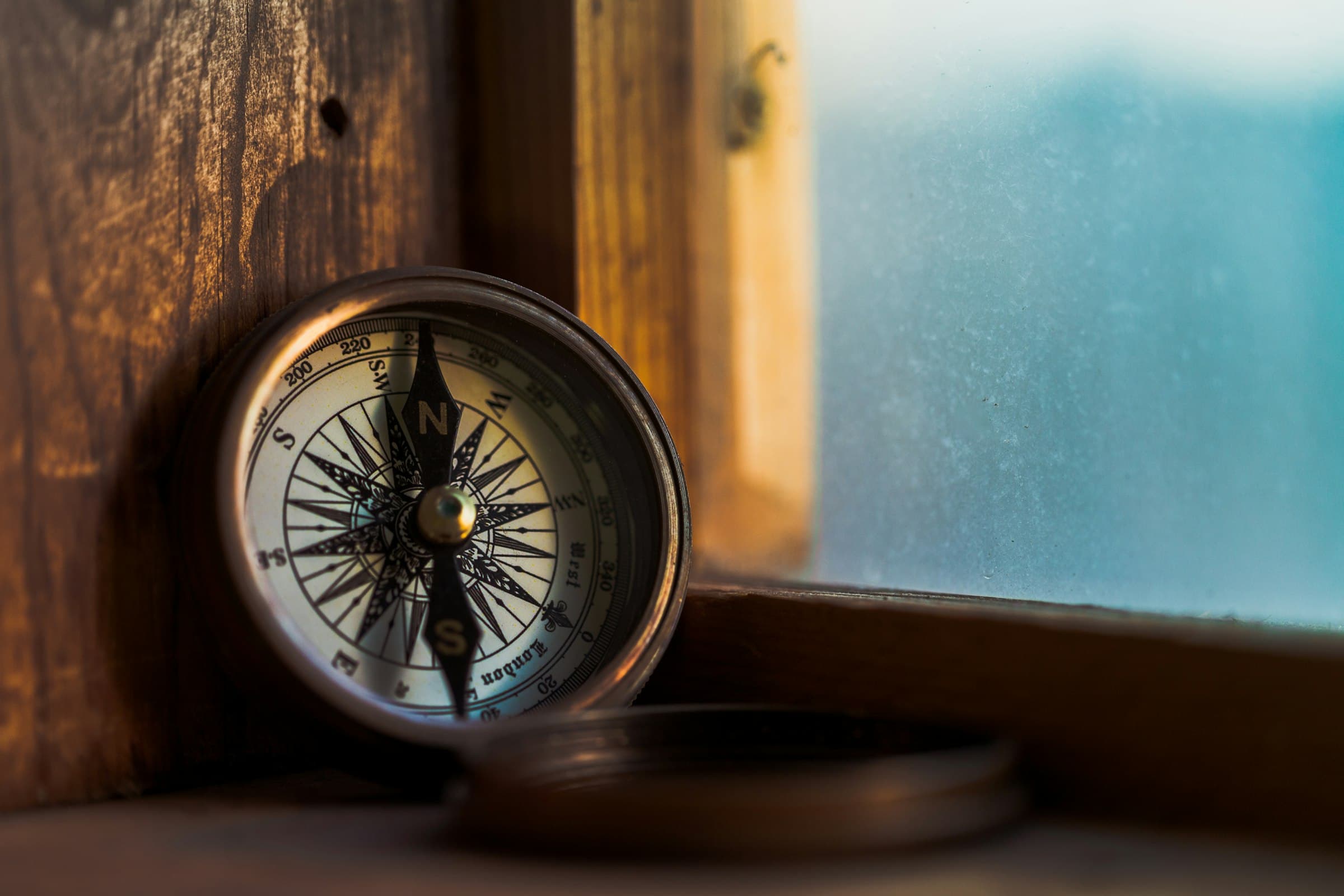 Round vintage compass on a warm golden-lit wooden surface