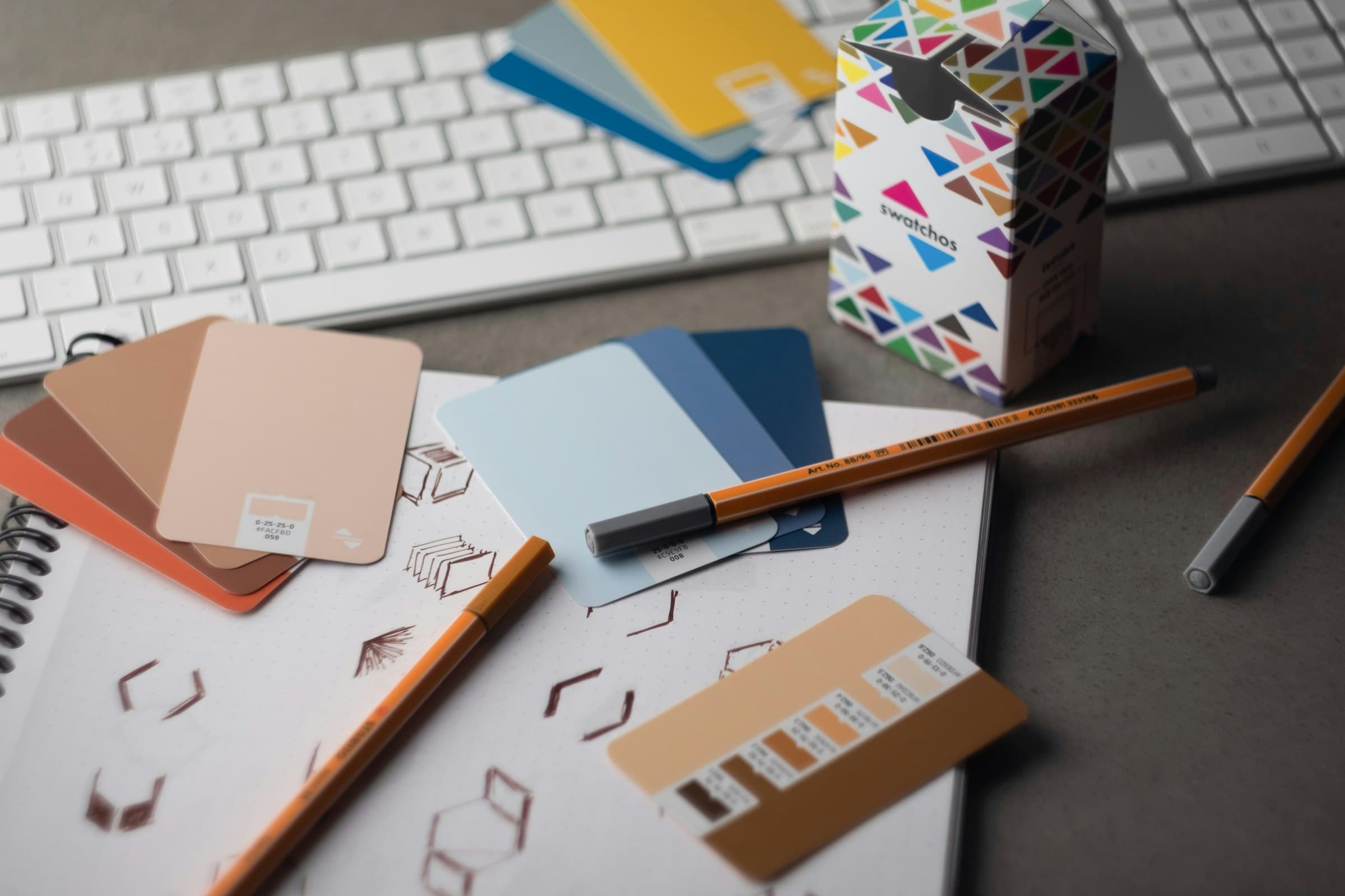 Designer desk with keyboard, pencils, and color swatch cards laid out
