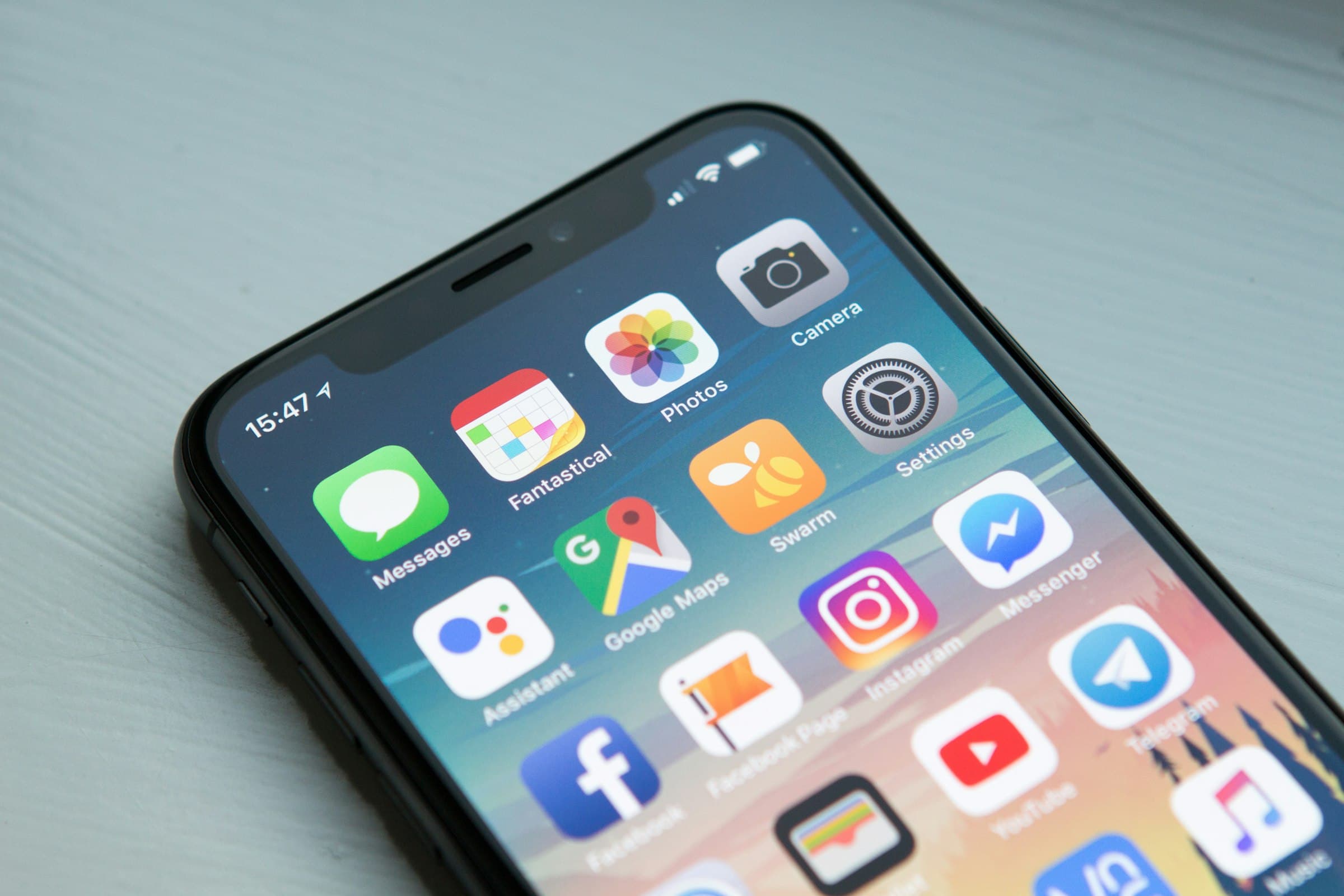 Space gray iPhone displaying app icons against a soft neutral surface